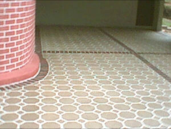 Beige and tan patterned floor with red brick pillar and border.