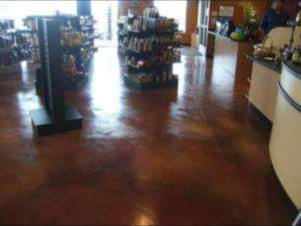 Polished, reddish-brown concrete floor in a retail store with shelves of products and display fixtures.