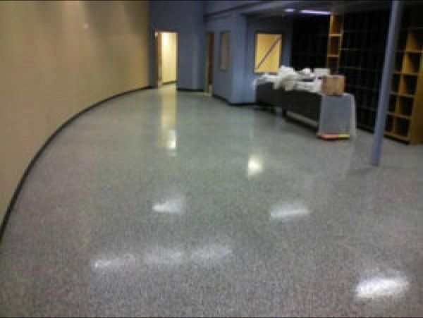 Polished concrete floor in a room with curved wall, doors, shelving, and a counter.