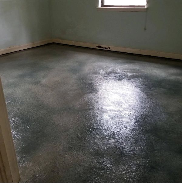Room with a dark, shiny, mottled gray and white concrete floor and pale blue walls.