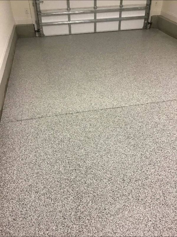 Gray speckled epoxy garage floor with a garage door in the background.