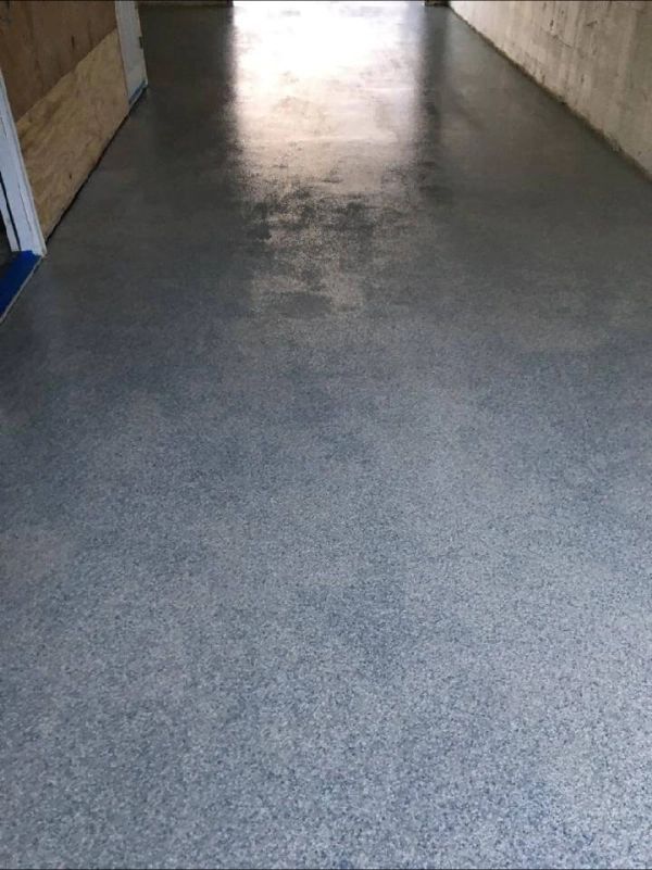 Gray epoxy floor in a hallway with shiny reflections.