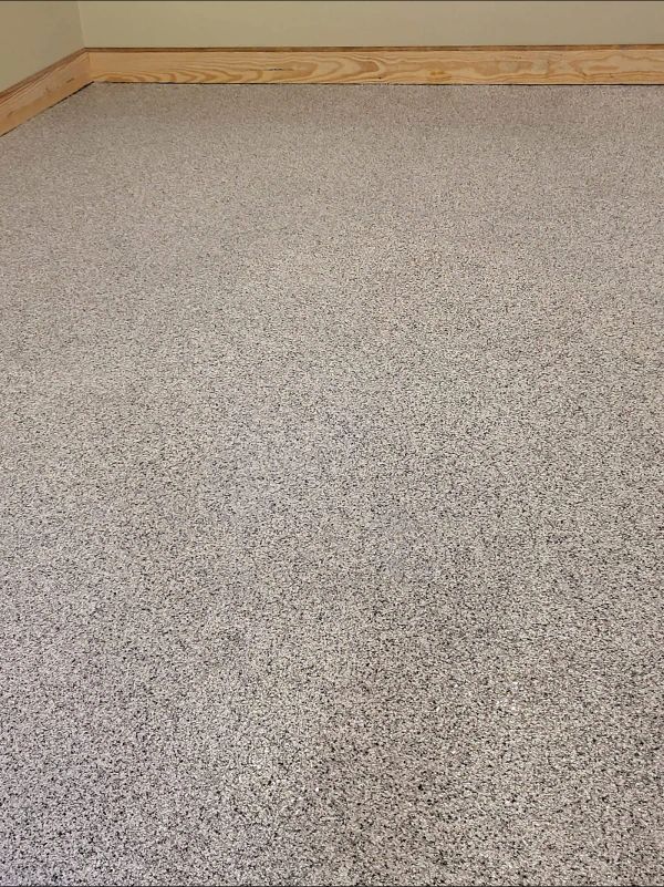 Gray speckled carpeted floor with wood trim at top.