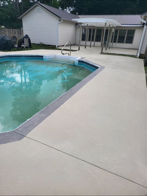 Pool with concrete deck, house in background. Gray and light beige tones.