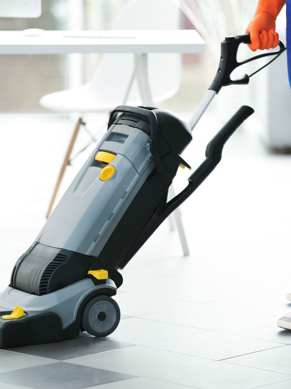 Persona che utilizza una macchina per la pulizia dei pavimenti commerciali grigia e nera in un ufficio.
