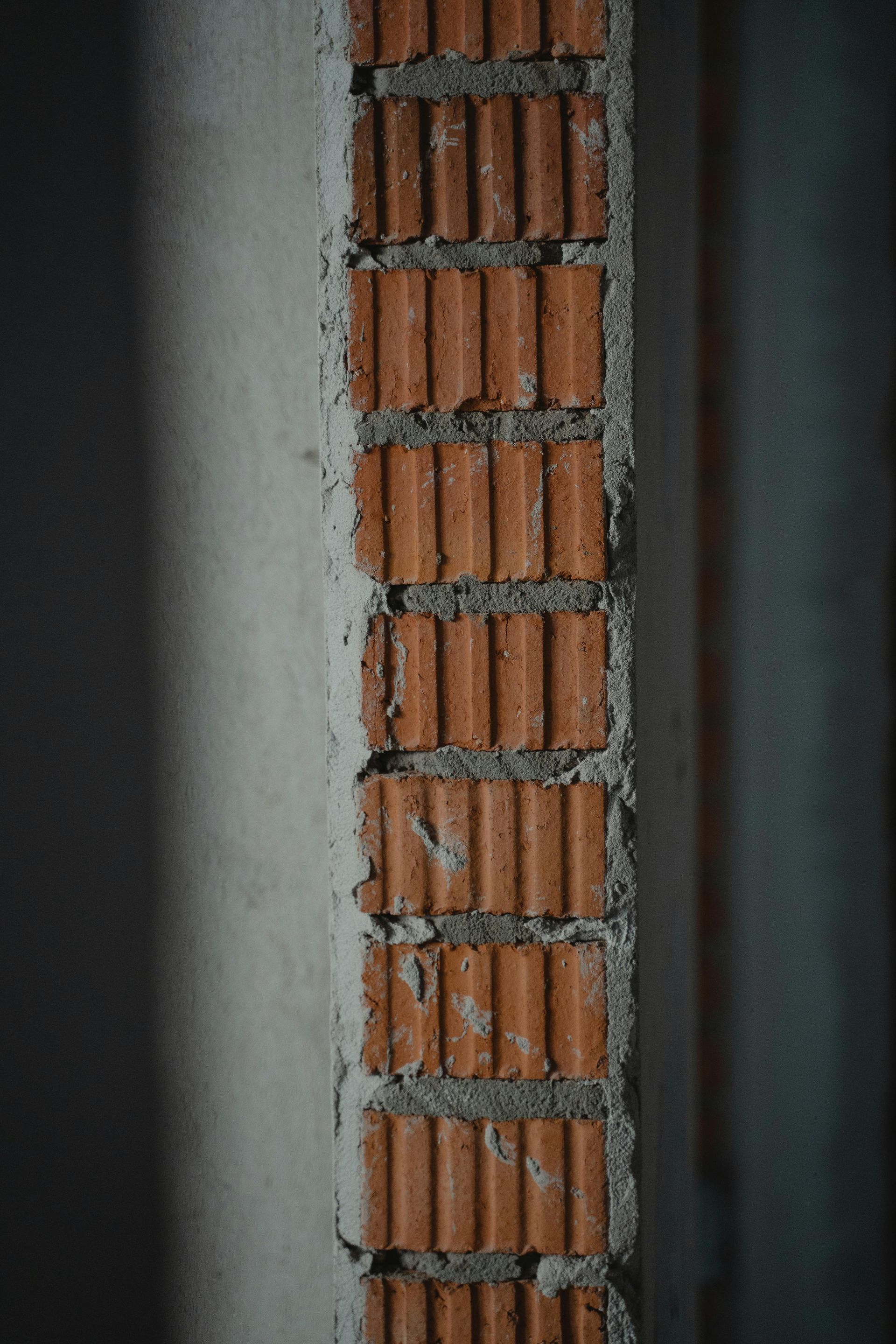 Brick wall under construction, vertical with light gray concrete and red-brown bricks.