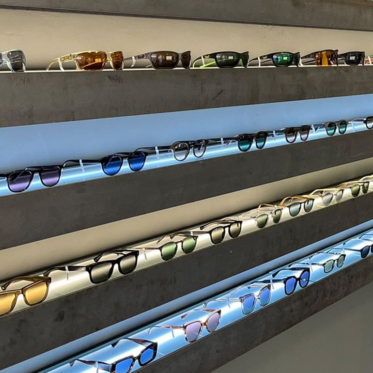 Sonnenbrillen werden in einem Geschäft auf beleuchteten Regalen ausgestellt.