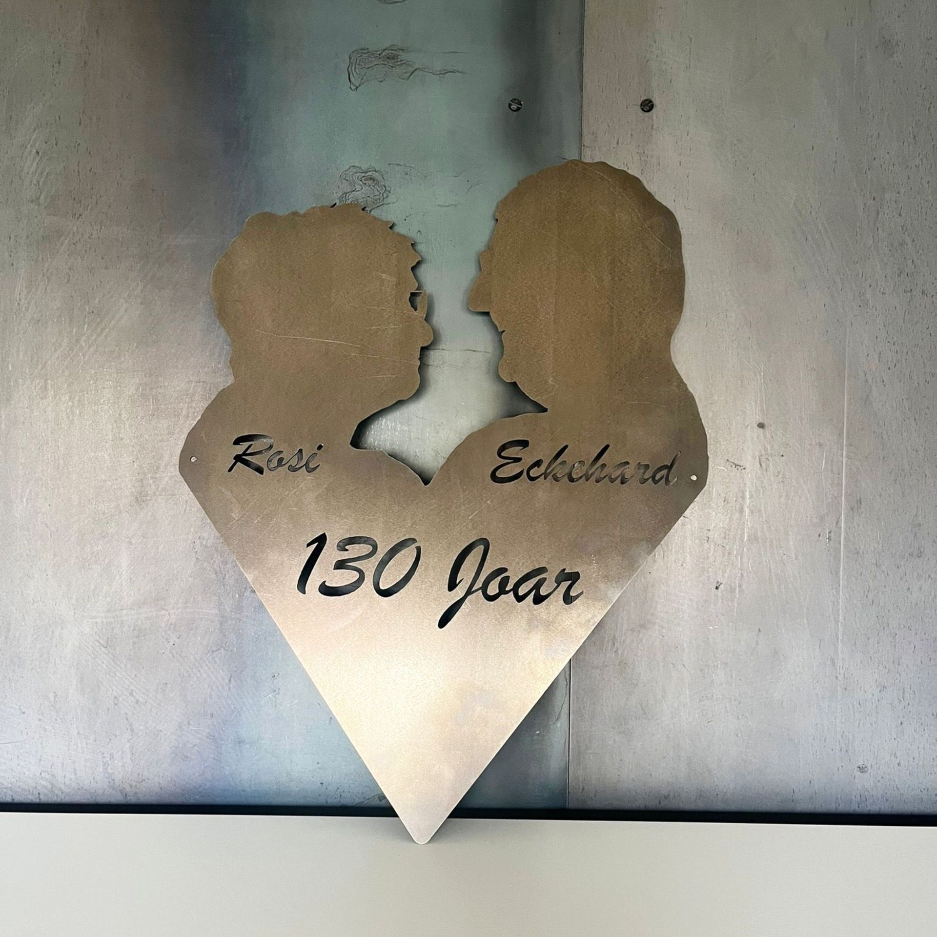 Metallherz mit den Silhouetten eines Paares, den Namen „Rosi“ und „Eckhard“ sowie dem Schriftzug „130 jaar“ 