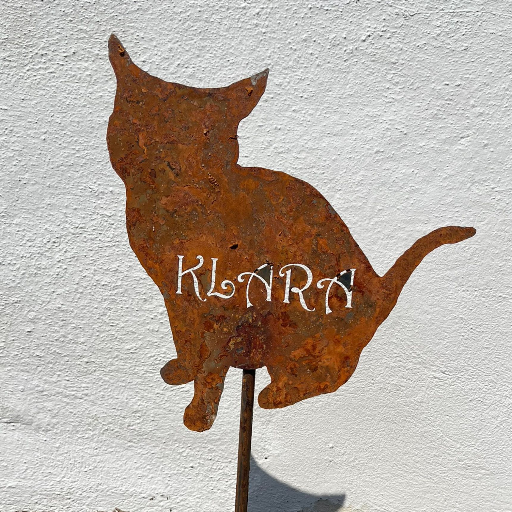 Rostige Metallkatze als Gartendekoration mit dem Schriftzug „KLARA“ in Weiß.