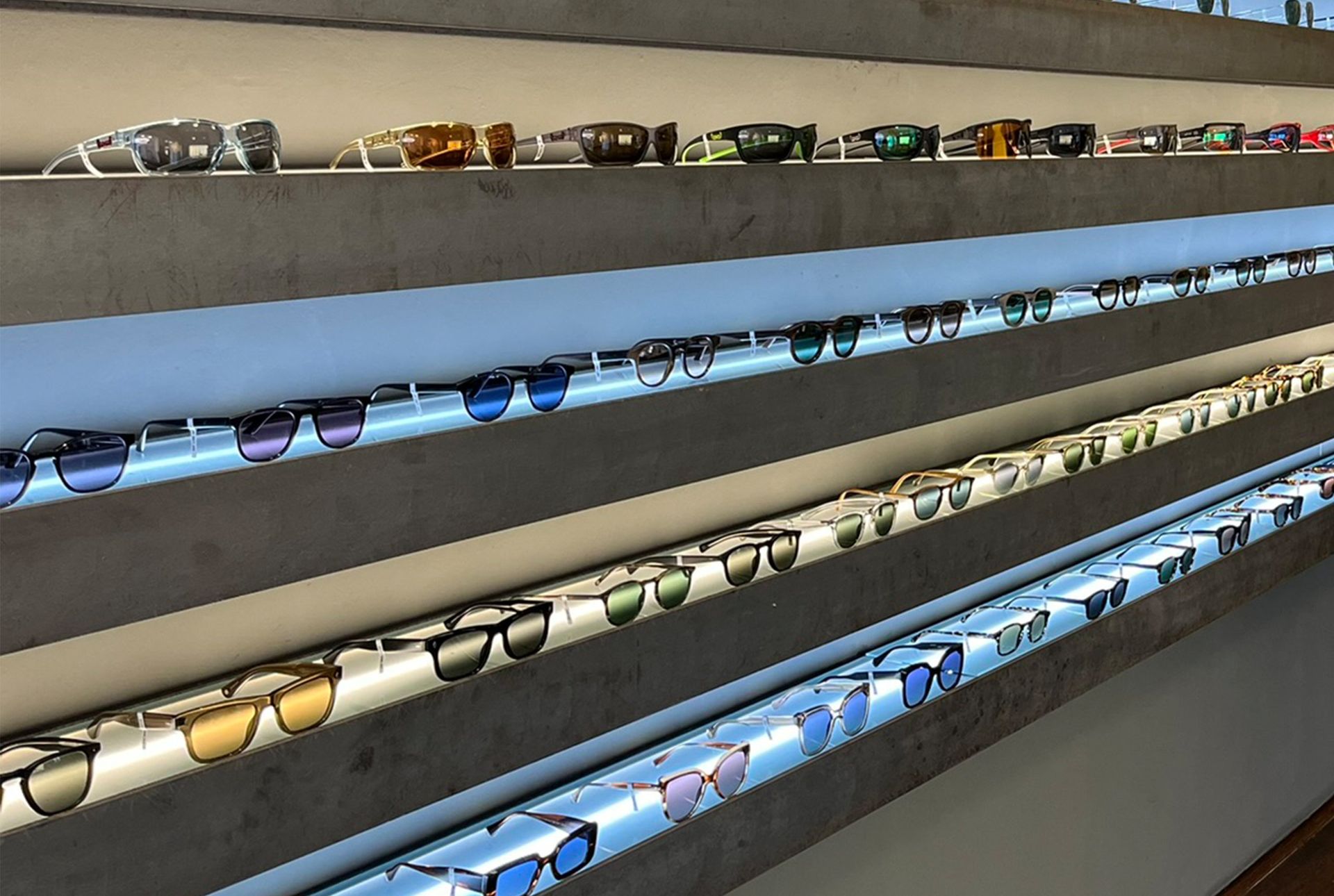 Sonnenbrillen werden auf beleuchteten Regalen präsentiert.