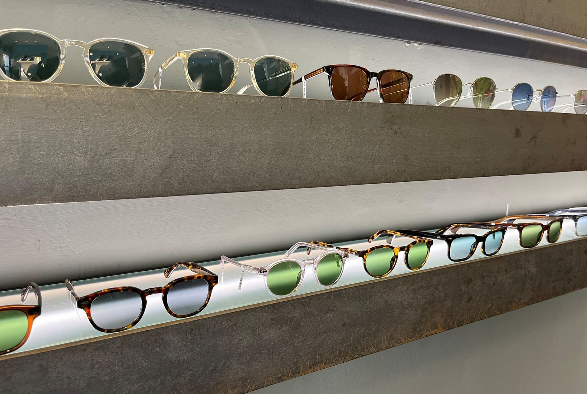 Sonnenbrillen sind in einem Geschäft in Regalen ausgestellt. Mehrere Gestelle, verschiedene Stile und Farben, die von der Innenbeleuchtung angestrahlt werden.