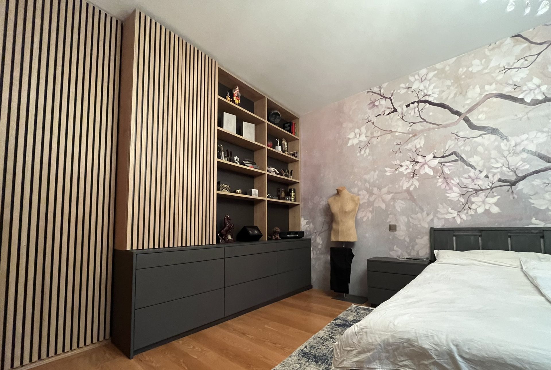 Modernes Schlafzimmer mit holzgetäfeltem Kleiderschrank, offenen Regalen, Kommode, floraler Tapete und Bett.