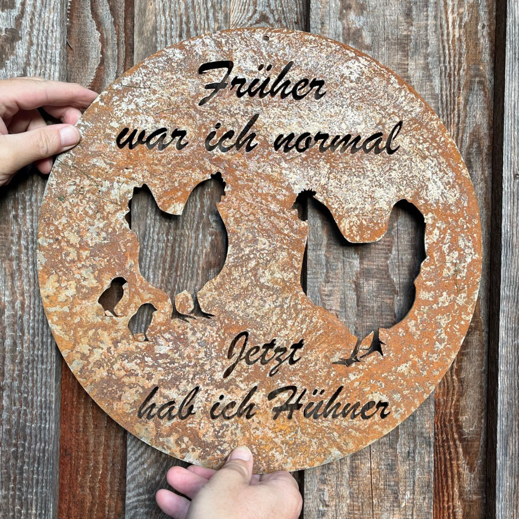 Rostiges Metallschild mit Hühnerausschnitten und deutschem Text: „Früher war ich normal. Jetzt habe ich Hühner.“