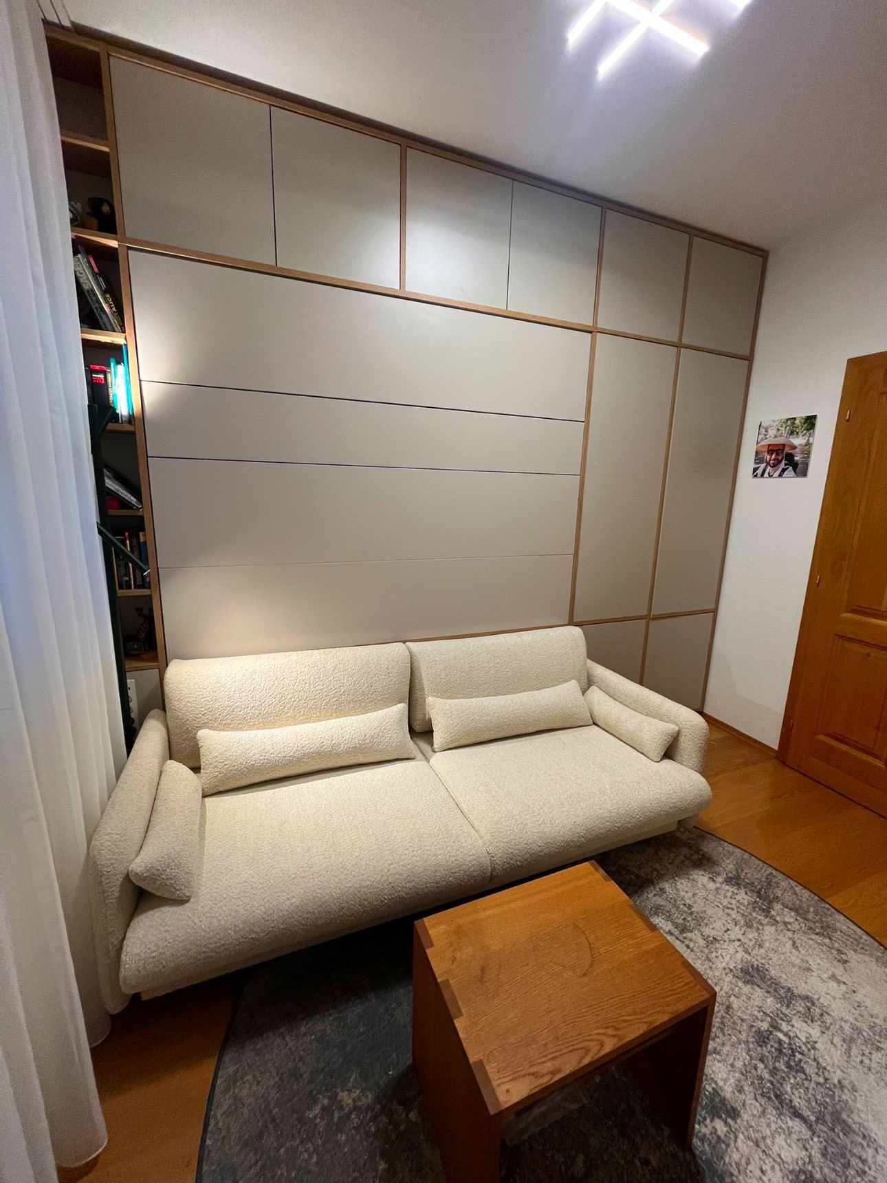 Beigefarbenes Sofa in einem Zimmer mit Holzvertäfelung und einem kleinen Holztisch auf einem Teppich.