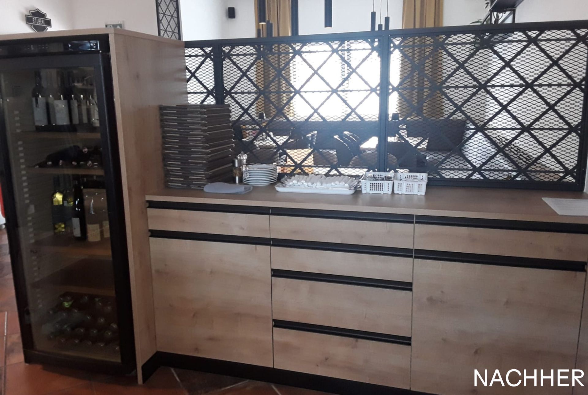 Holzschrank mit Weinkühler, Gläsern und dekorativem Gitterwerk im Esszimmer.