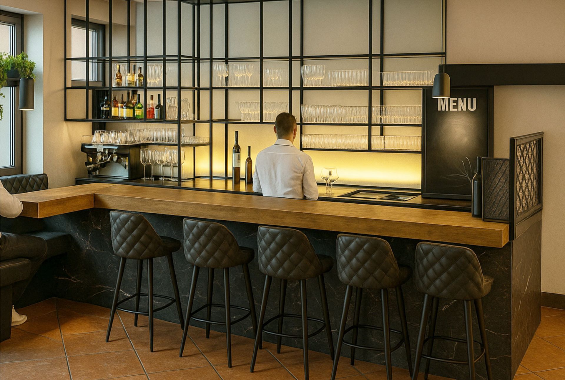 Bar mit Barkeeper hinter der Theke, schwarz-goldener Dekoration und Sitzgelegenheiten mit gesteppten Hockern.