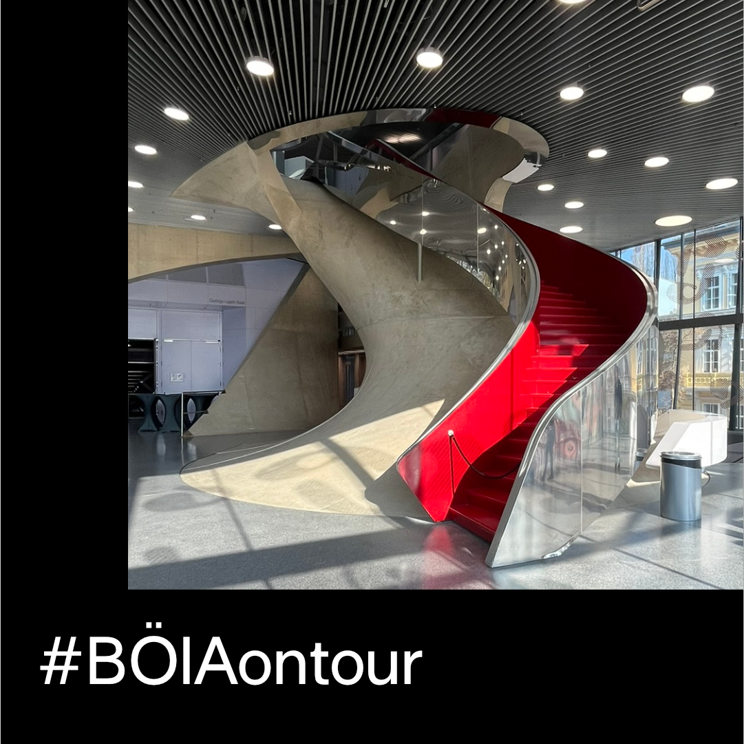 Eine moderne, rot-silberne Wendeltreppe in einem Gebäude; Hashtag #BÖlAontour.