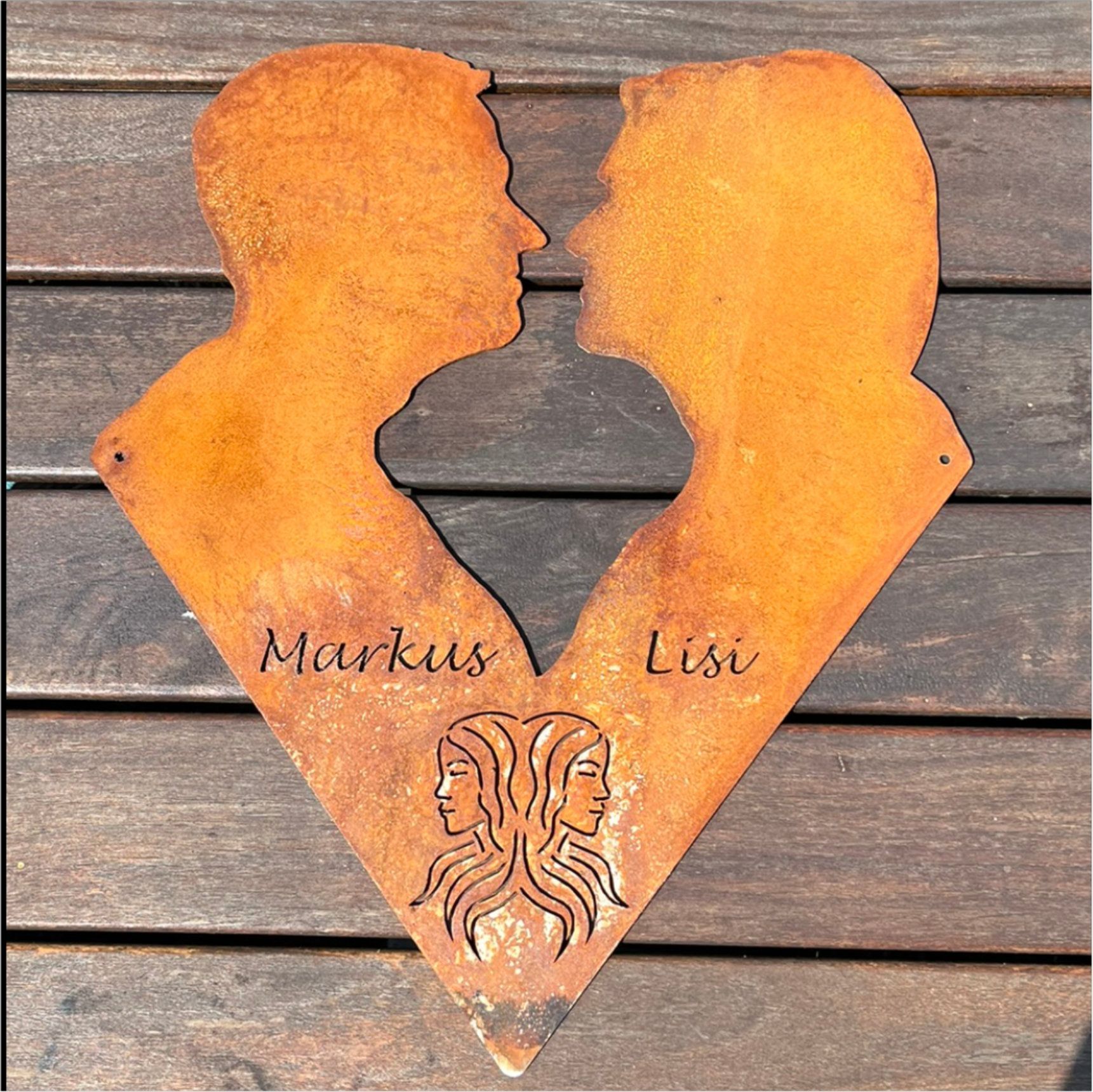 Herzförmiges Kunstwerk aus rostigem Metall mit zwei einander zugewandten Profilen; „Markus“ und „Lisi“, Symbol des Zwillings.