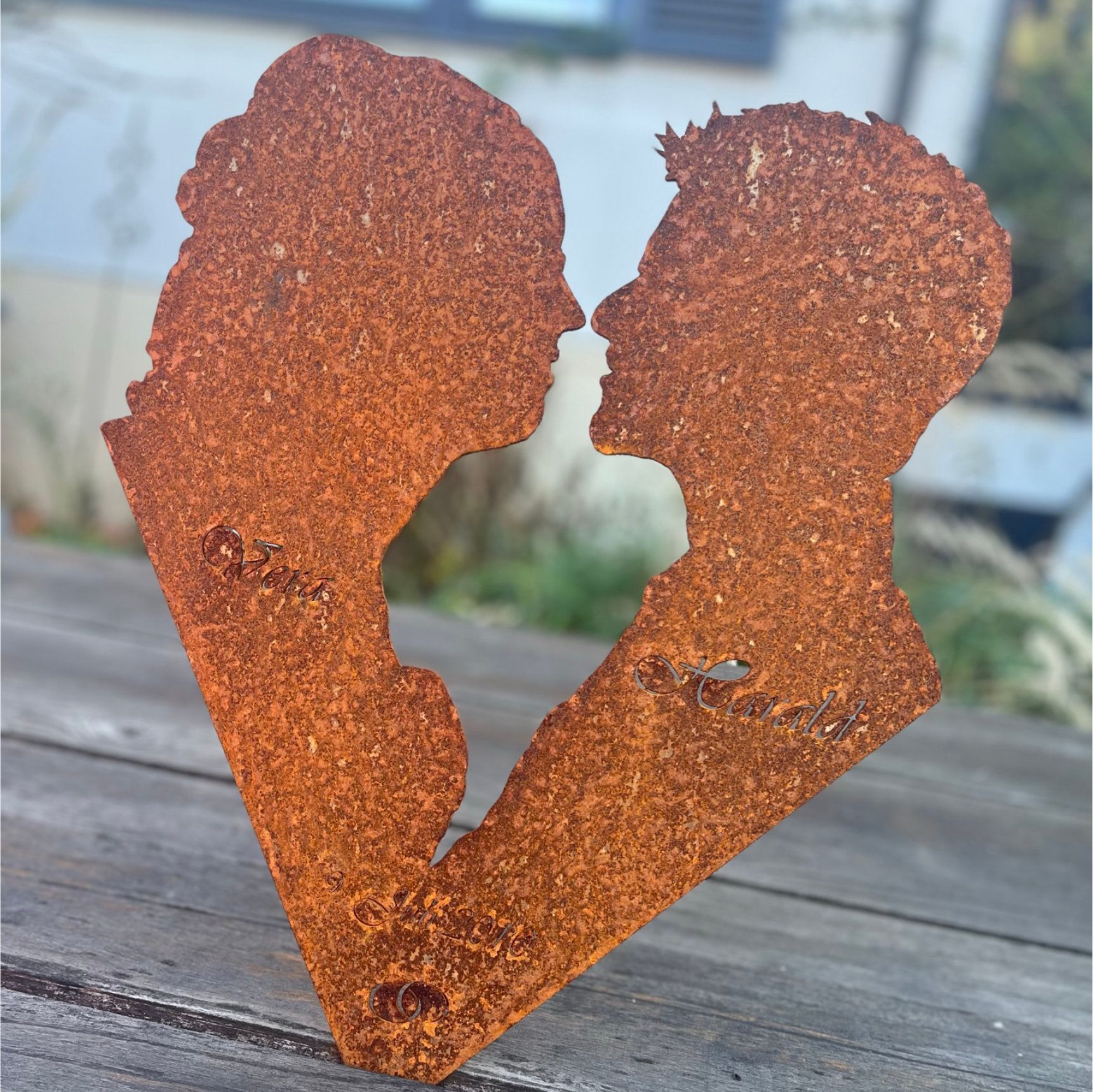 Skulptur eines rostigen Metallherzens mit zwei einander zugewandten Profilen.