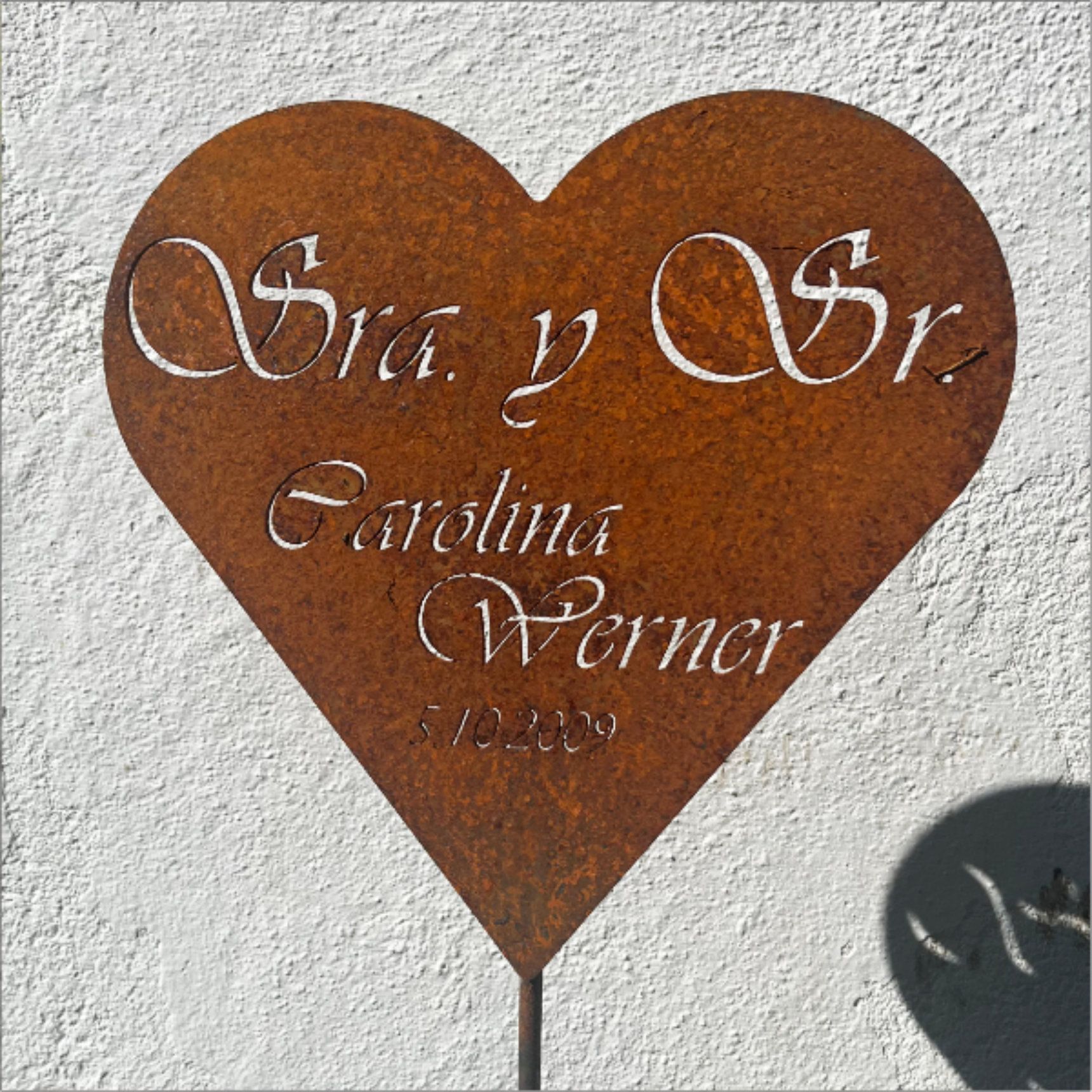 Verrostetes, herzförmiges Schild mit der Aufschrift „Sra. y Sr. Carolina Werner 7.10.2009“; steht draußen.