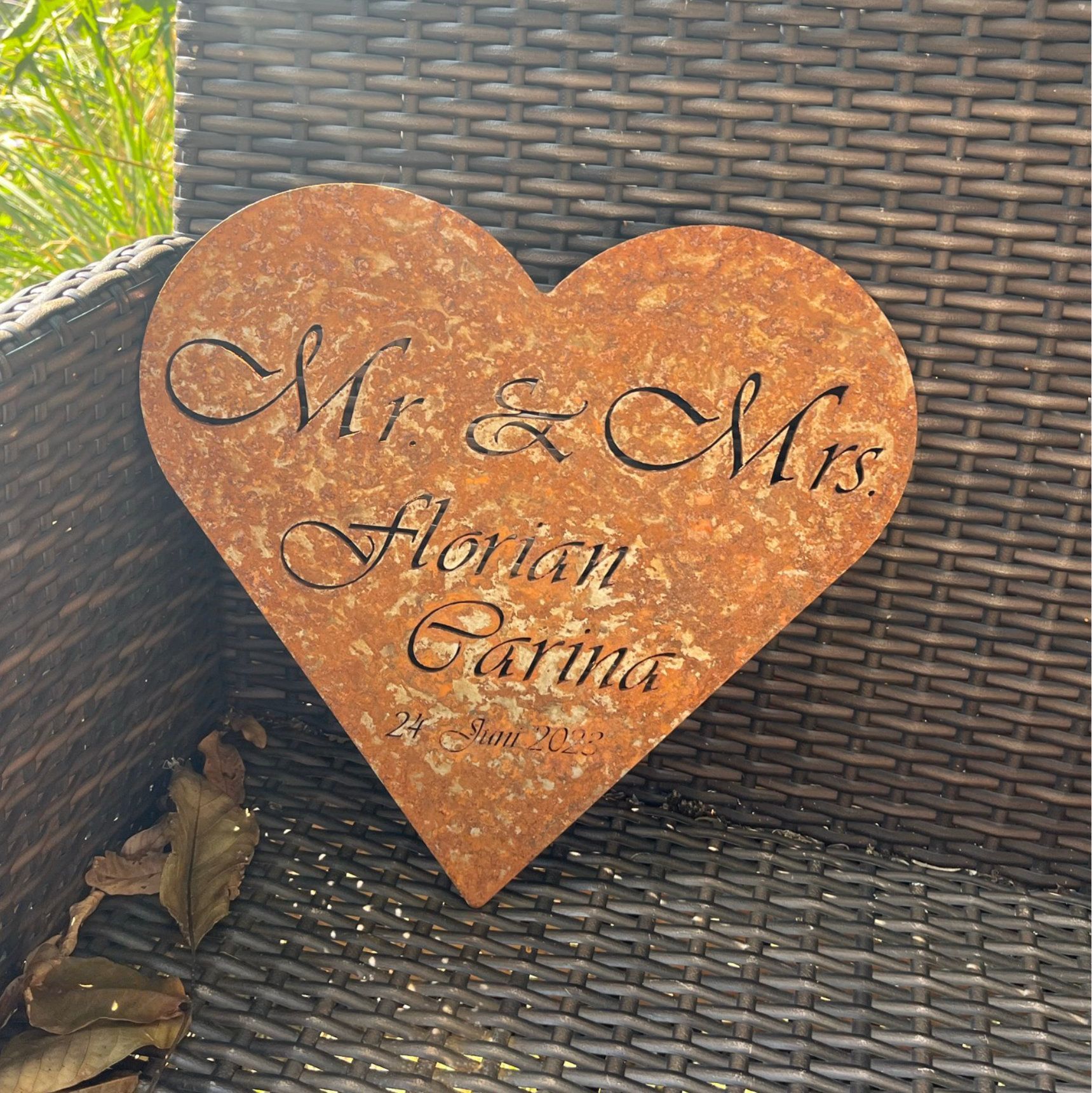 Rostiges, herzförmiges Schild mit der Aufschrift „Mr. & Mrs. Florian Carina“ und ausgeschnittenem Datum.