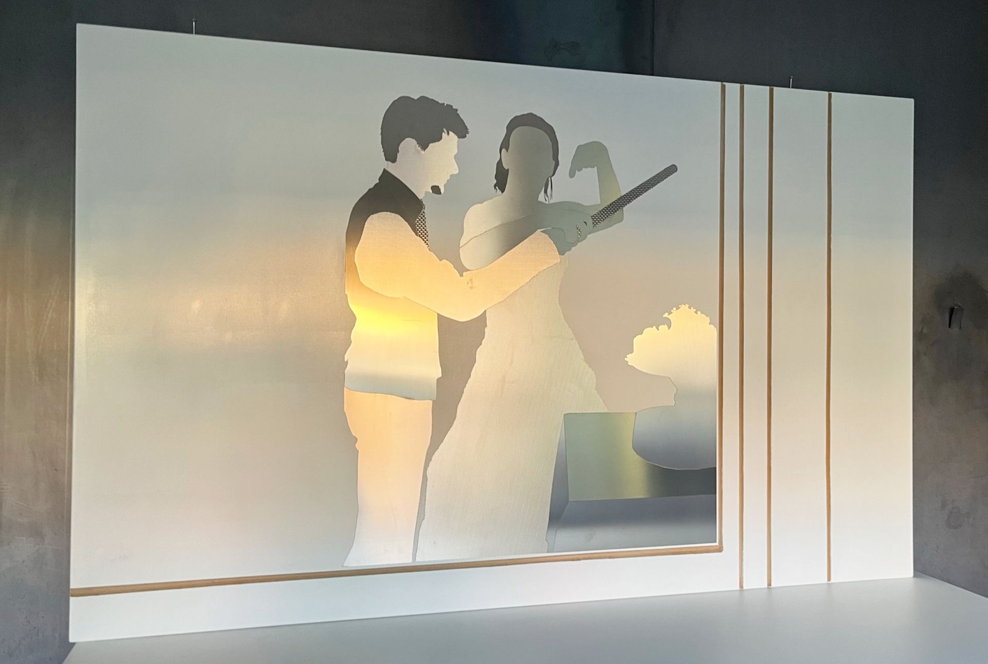 Ein im Schattenriss dargestelltes Paar bewundert einen Blumenstrauß auf einer Milchglasscheibe mit vertikalen Goldstreifen.