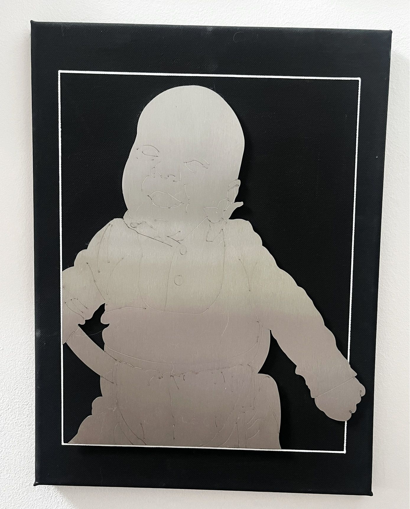 Silhouette einer Person mit einer Hand in der Hüfte, aus metallischem Material auf schwarzem Hintergrund ausgeschnitten