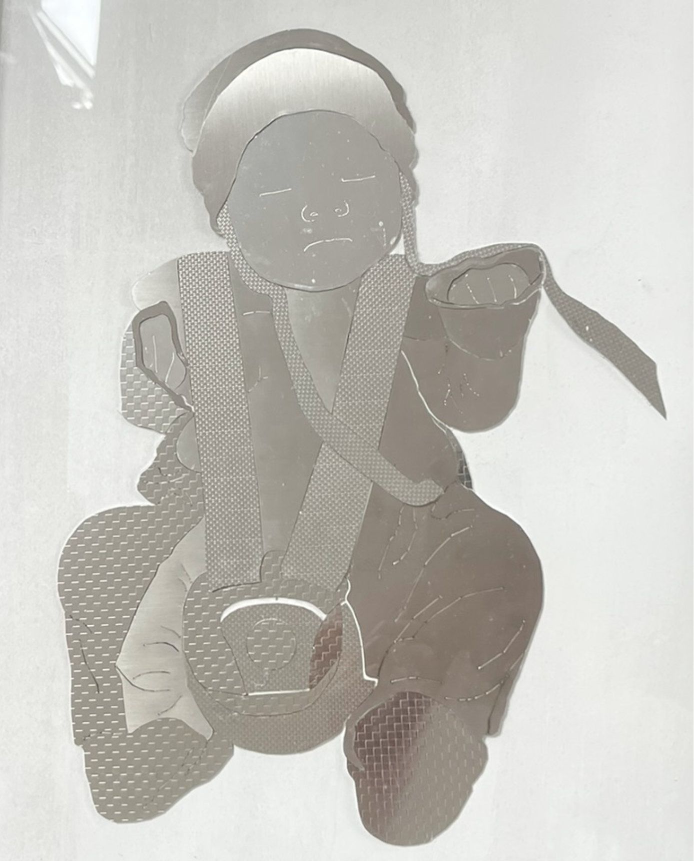 Ein sitzendes Baby mit strukturierter Oberfläche, das einen Gegenstand hält und ein Band auf dem Kopf trägt.