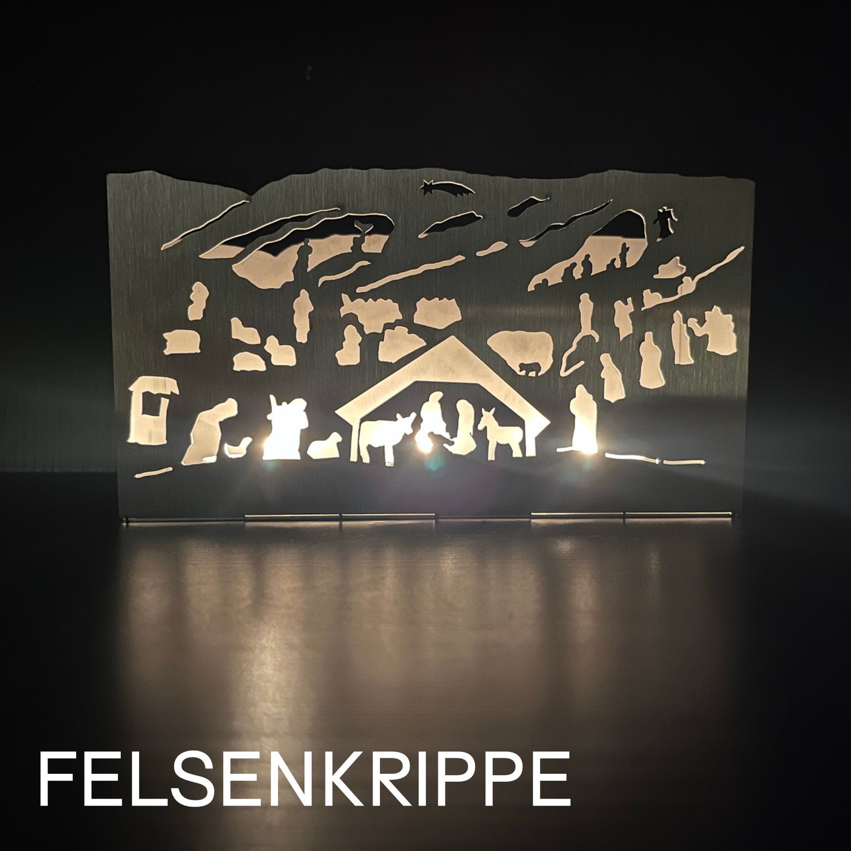 Silhouette einer Krippenszene, von innen beleuchtet, mit dem Schriftzug „FELSENKRIPPE“ am unteren Rand.