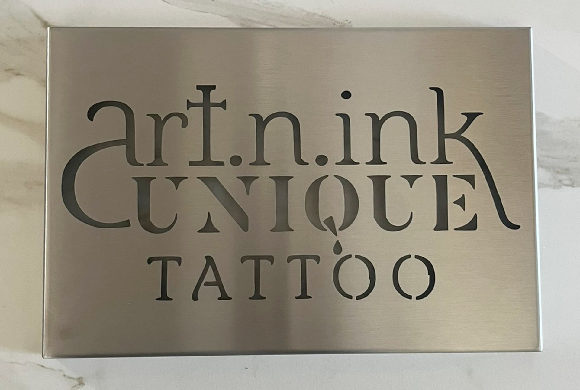 Schild aus Edelstahl, Aufschrift „art.n.ink UNIQUE TATTOO“.