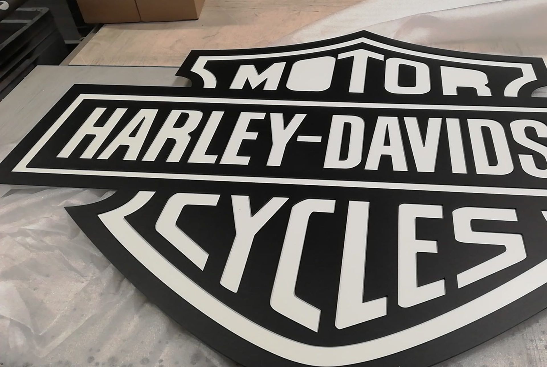 Großes schwarz-weißes Harley-Davidson-Schild mit dem Markenlogo.