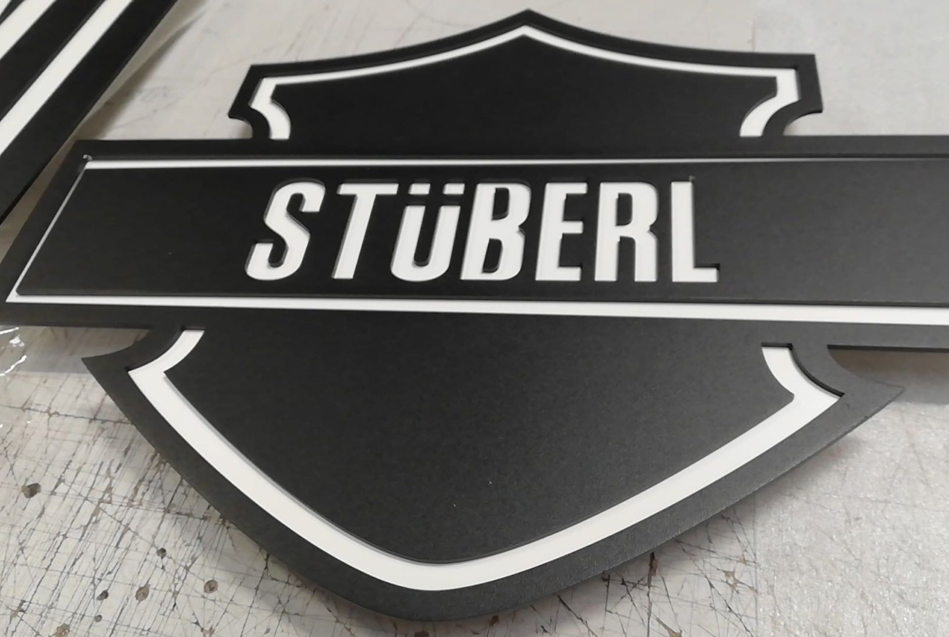 Schwarz-weißes Schild mit dem Wort „STÜBERL“ in weißer Schrift innerhalb eines schildförmigen Designs.