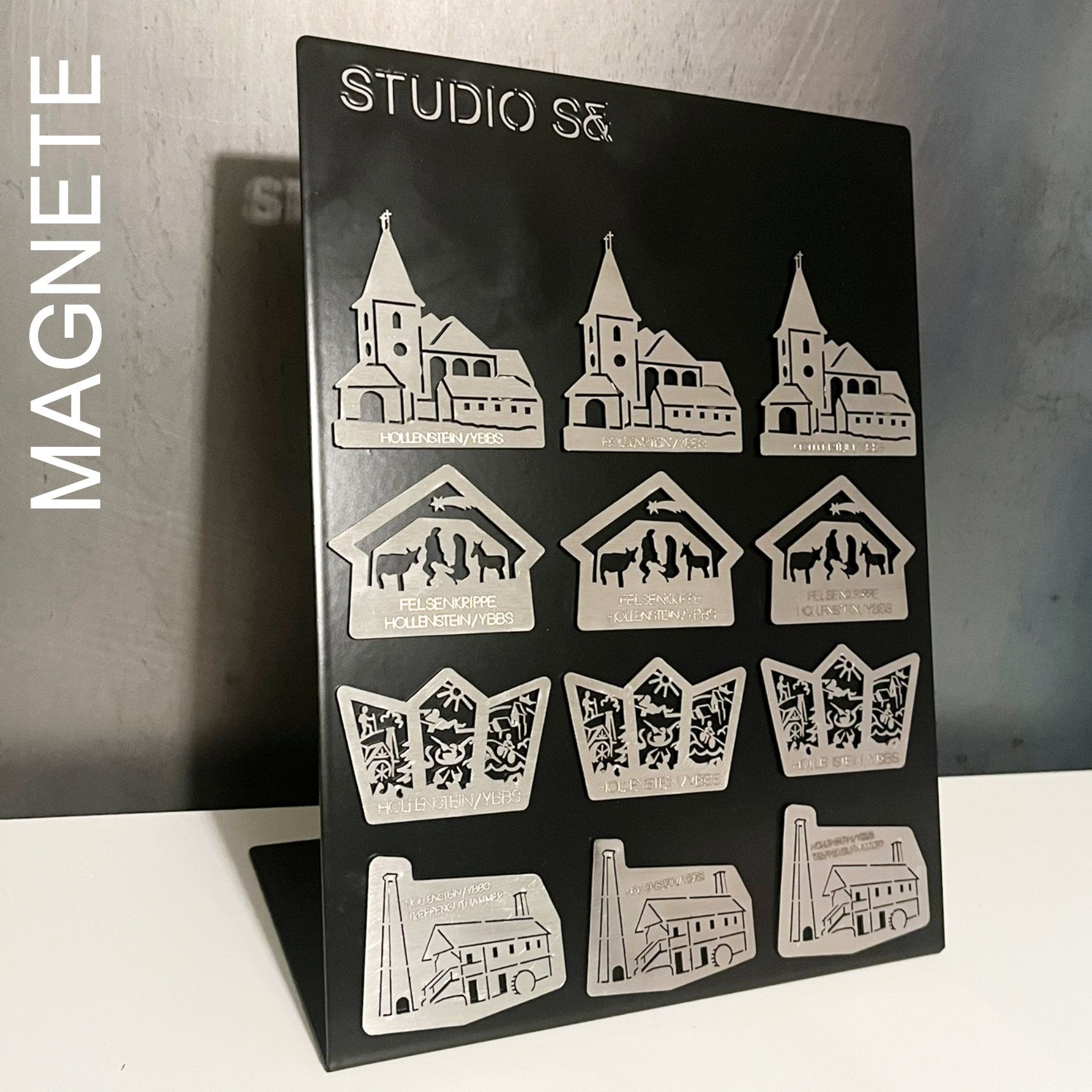 Metallmagnete mit Gebäudesilhouetten auf schwarzem Hintergrund.