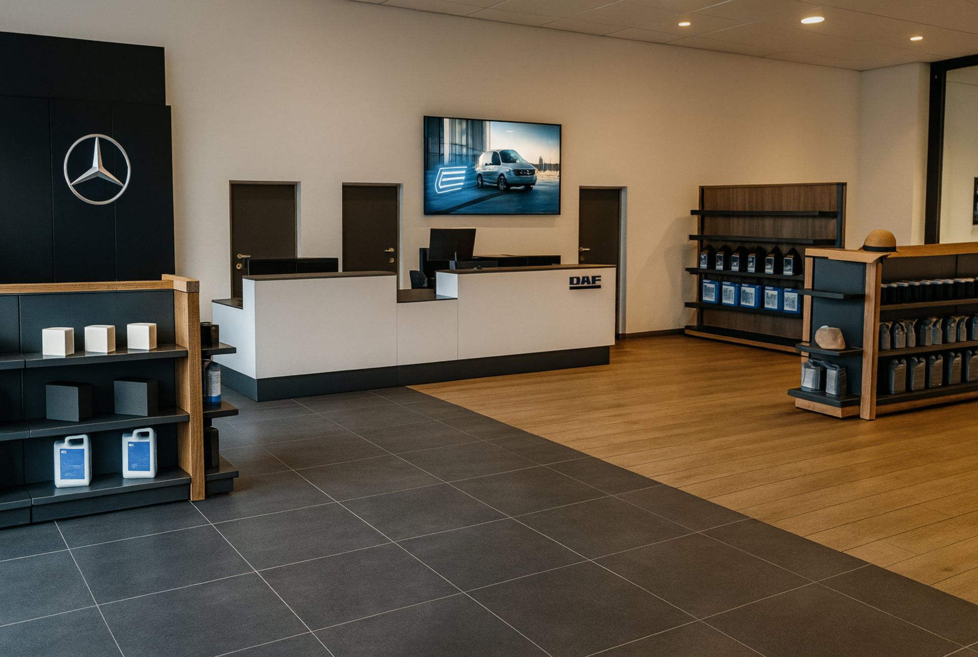 Innenansicht eines Mercedes-Benz-Autohauses: Ausstellungsraum mit Servicetheke, Produktpräsentationen und einem großen Bildschirm, auf dem ein Auto abgebildet ist.