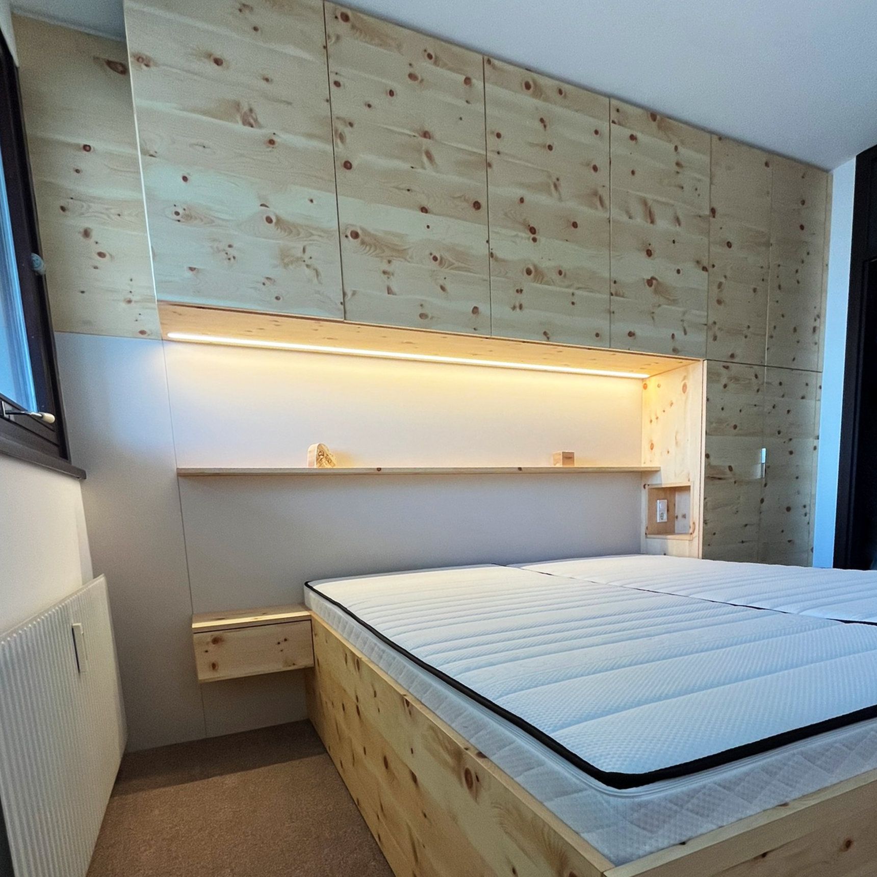 Therapieraum mit Massageliege, Naturwandbild, Holzboden und moderner Beleuchtung.