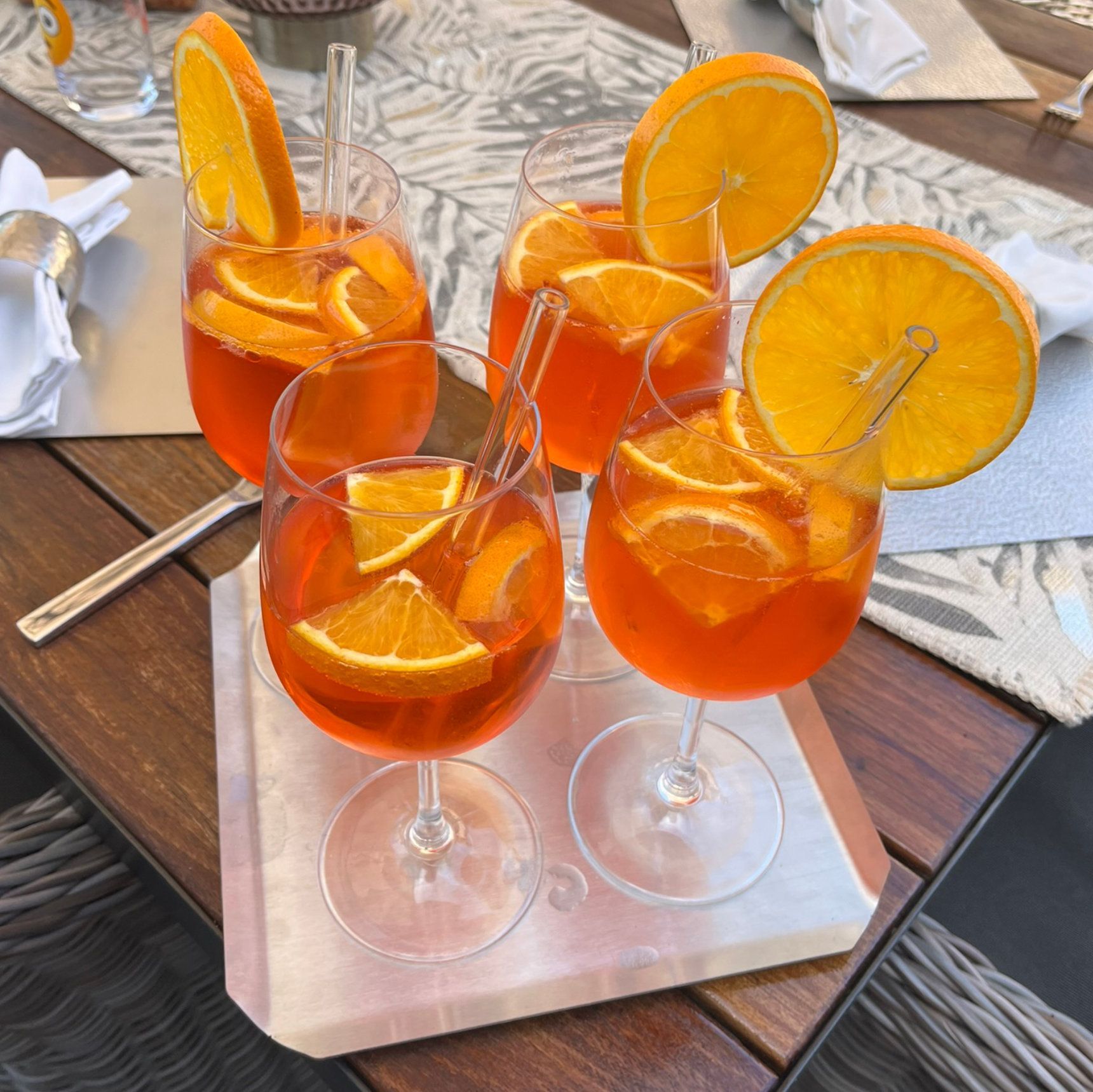 Fünf Aperol Spritz Cocktails mit Orangenscheiben in Weingläsern auf einem Tablett.