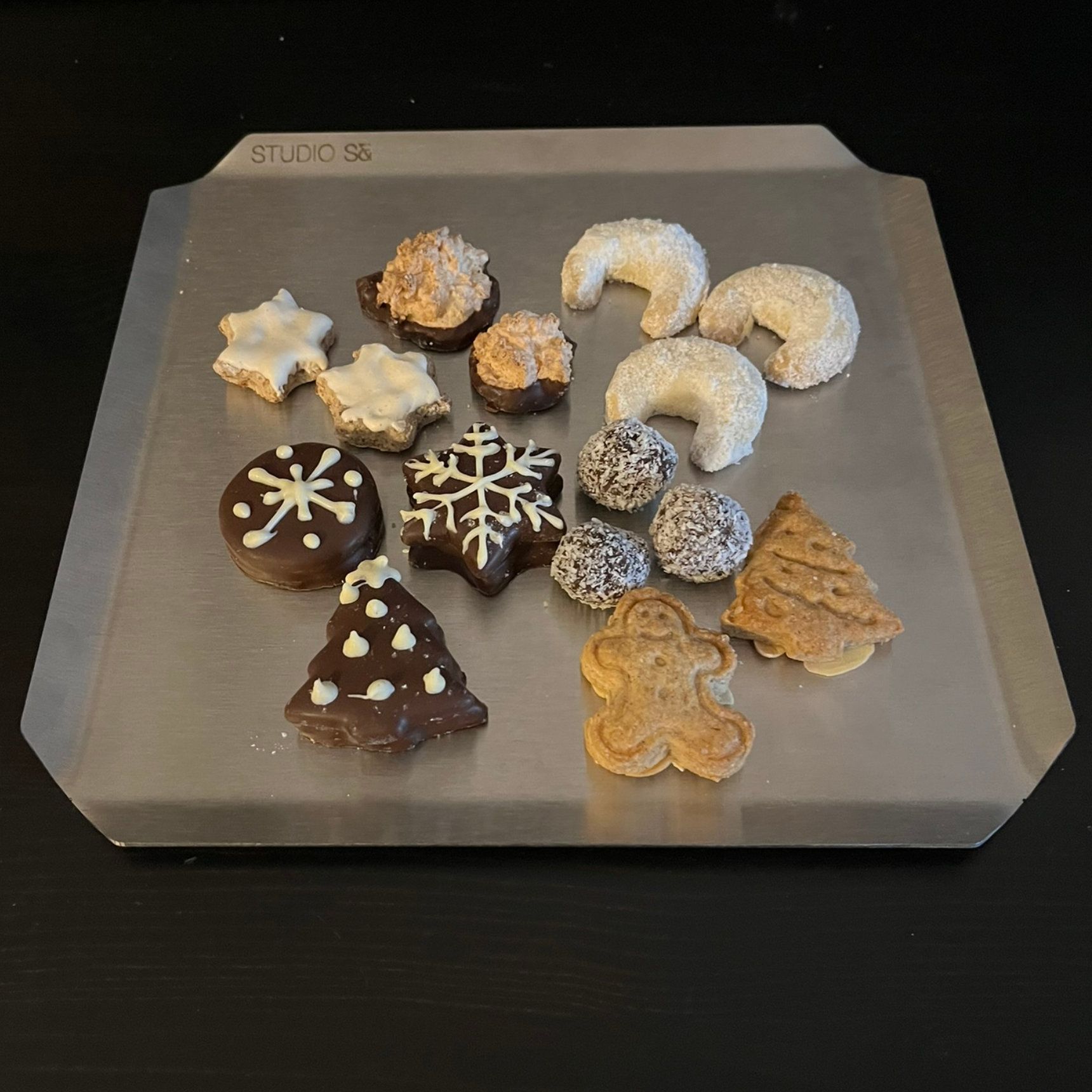 Eine Auswahl an Weihnachtsplätzchen auf einem silbernen Backblech. 