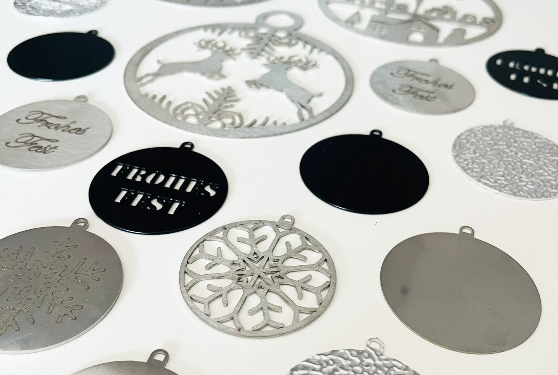 Verschiedene Weihnachtsornamente in Silber und Schwarz auf weißem Grund, mit Motiven wie Schneeflocken und Hirschen.
