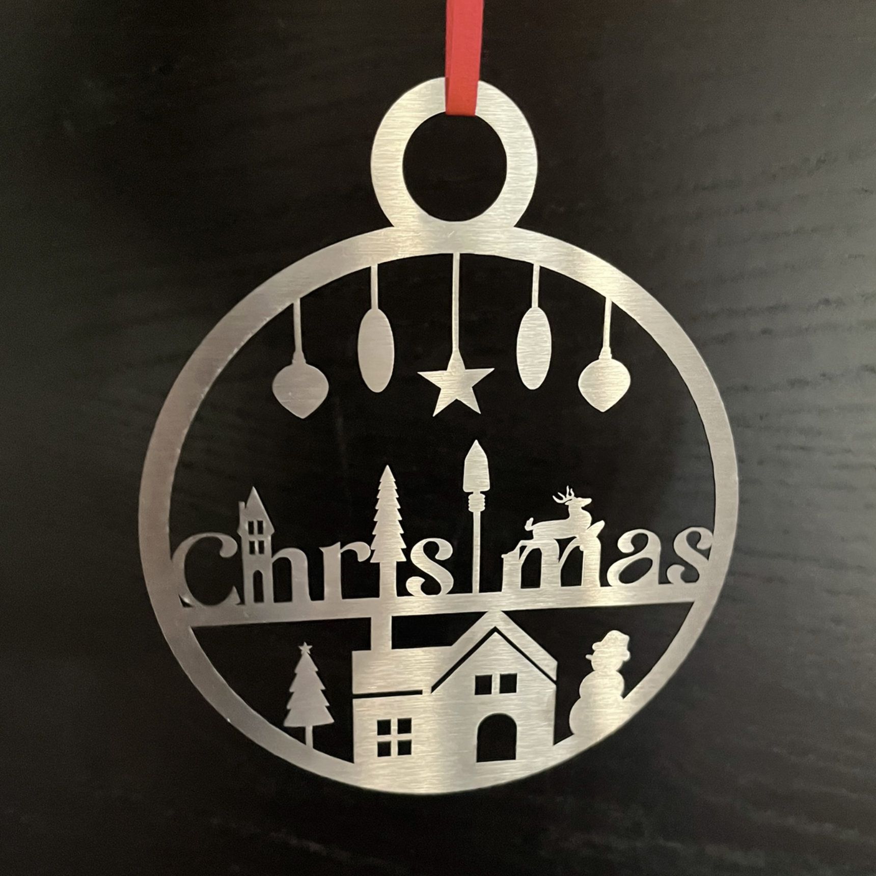 Silberner Weihnachtsschmuck mit Stadtmotiv, rotes Band.