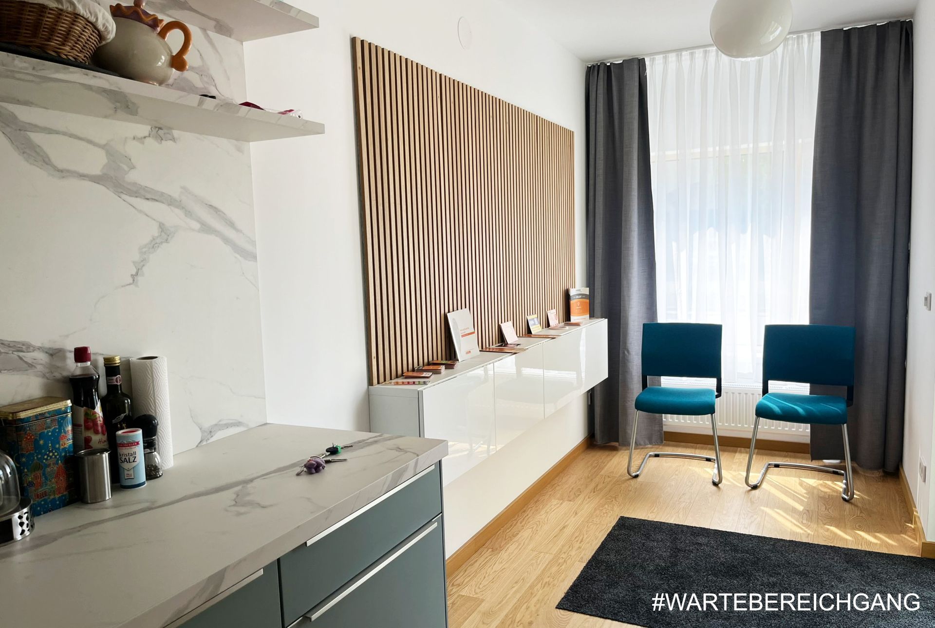 Raum mit Wartebereichsmöbeln, Holzboden und einer dekorativen Wand.