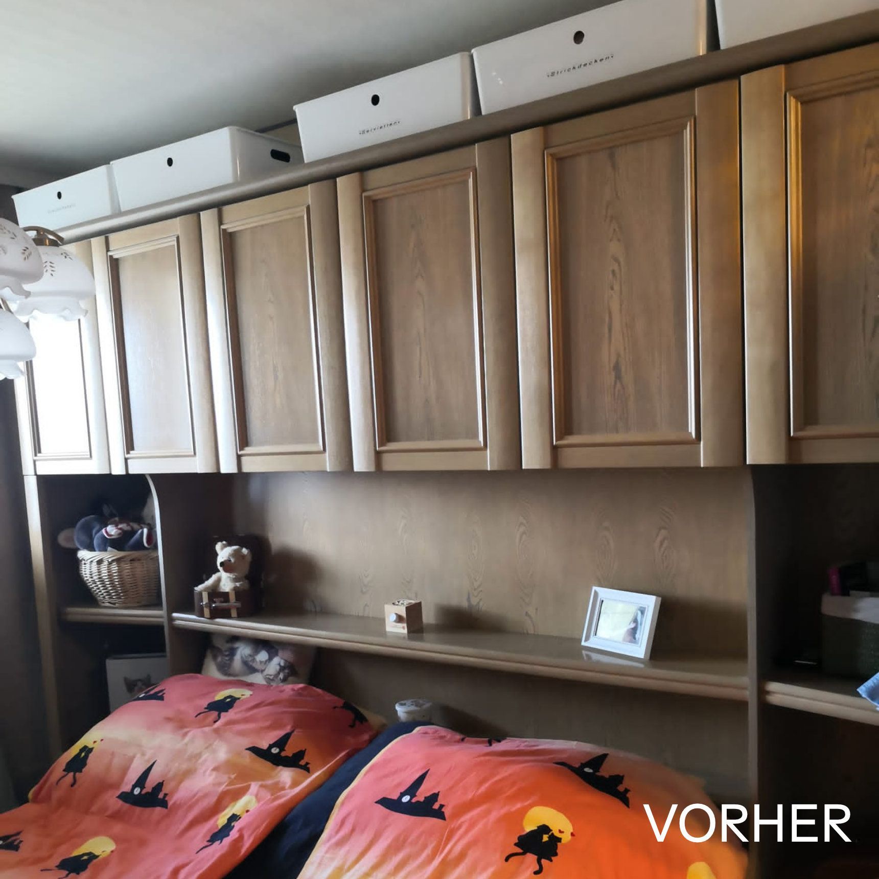 Schlafzimmer mit Einbauschrank mit Stauraum darüber, Bücherregalen und einem Bett mit orange-schwarzer Bettwäsche.