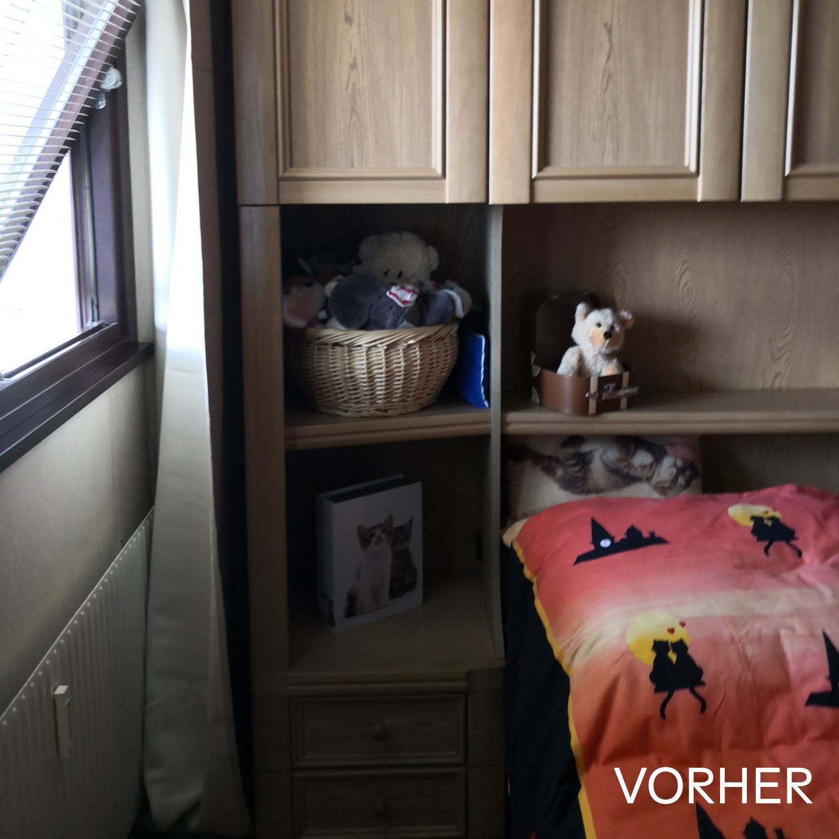 Schlafzimmermöbel mit eingebauten Regalen, in denen Stofftiere und ein Foto stehen. Rote und orangefarbene Bettwäsche ist zu sehen.