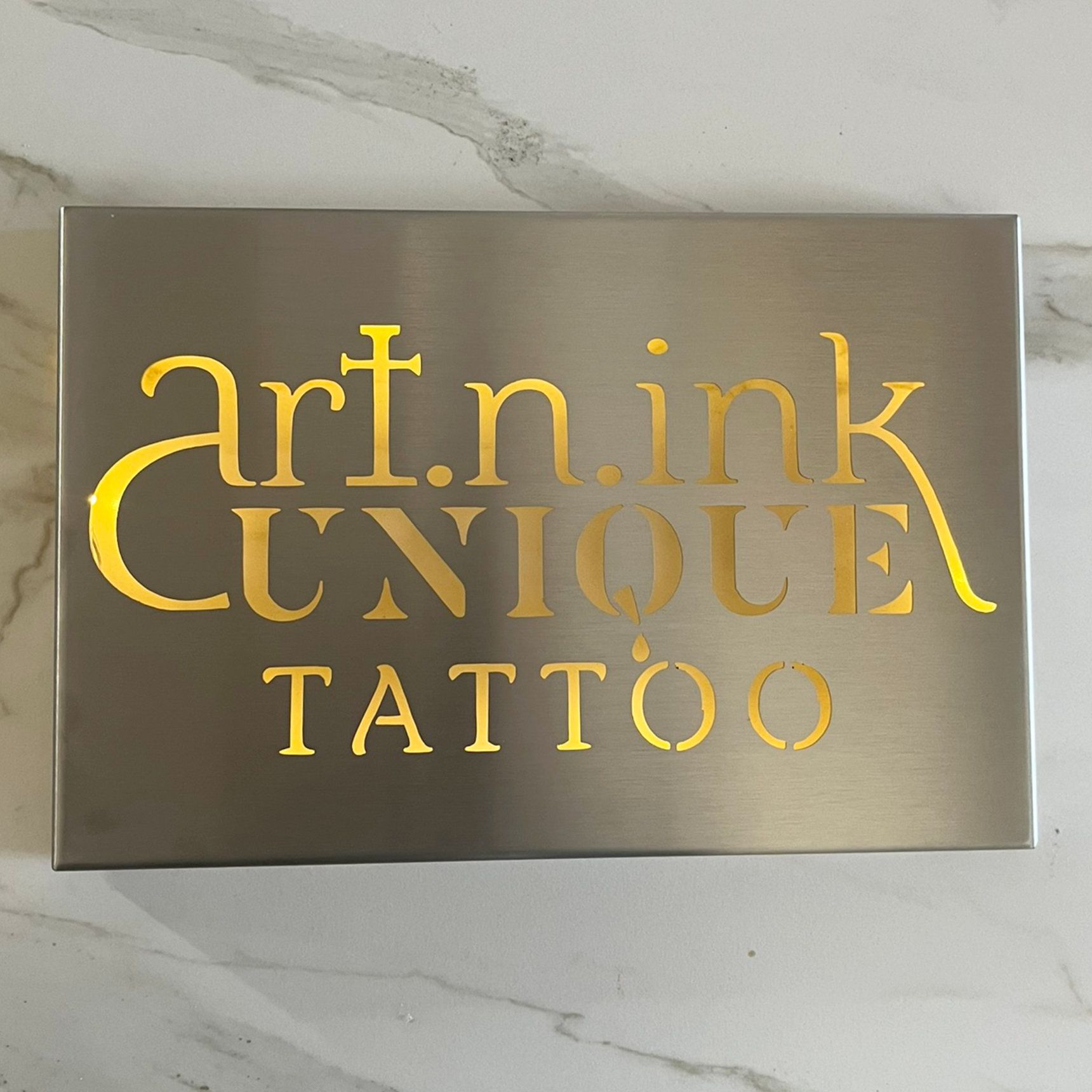 Schild aus gebürstetem Metall mit goldener Aufschrift: 