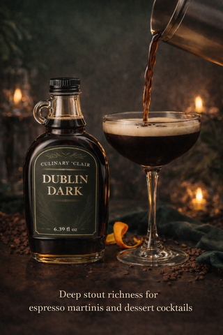 A bottle of Dublin Dark syrup next to a coupe glass being filled with a dark espresso martini on a moody, lit table.