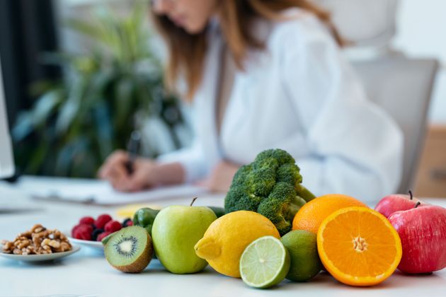 A dietitian writing notes behind a small pile of fruit