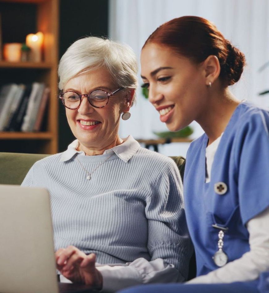 A Nurse in Blue Scrubs Helping a Senior with a Laptop
