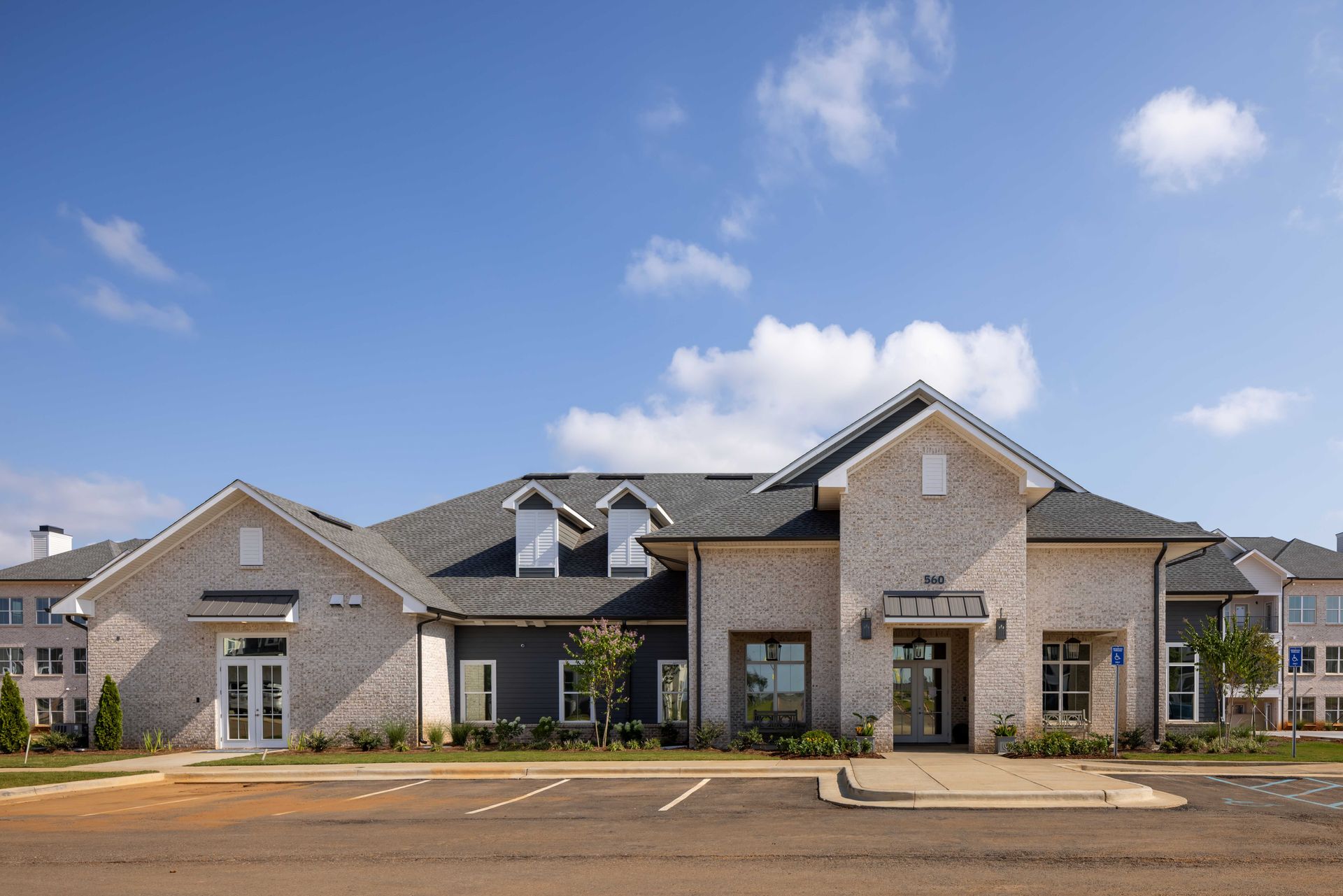 Brick building with blue door, windows, and parked cars under a blue sky.