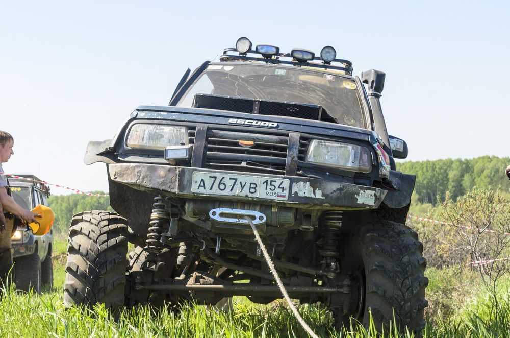 A man is pulling a jeep out of the mud with a winch.