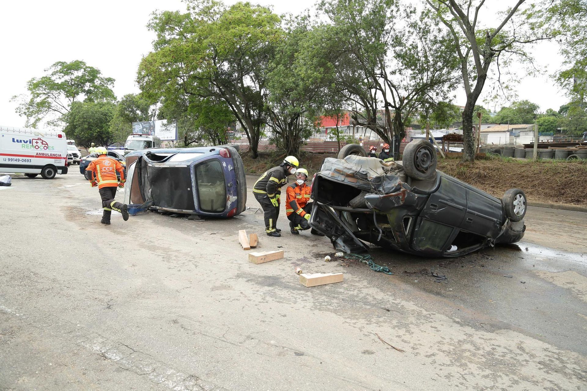 A car has rolled over on its side on the side of the road.