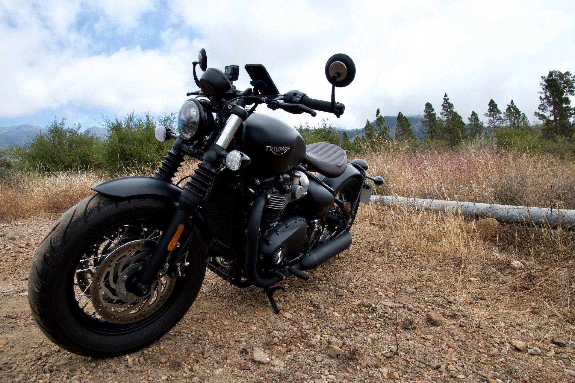 A black motorcycle is parked in a dirt field.